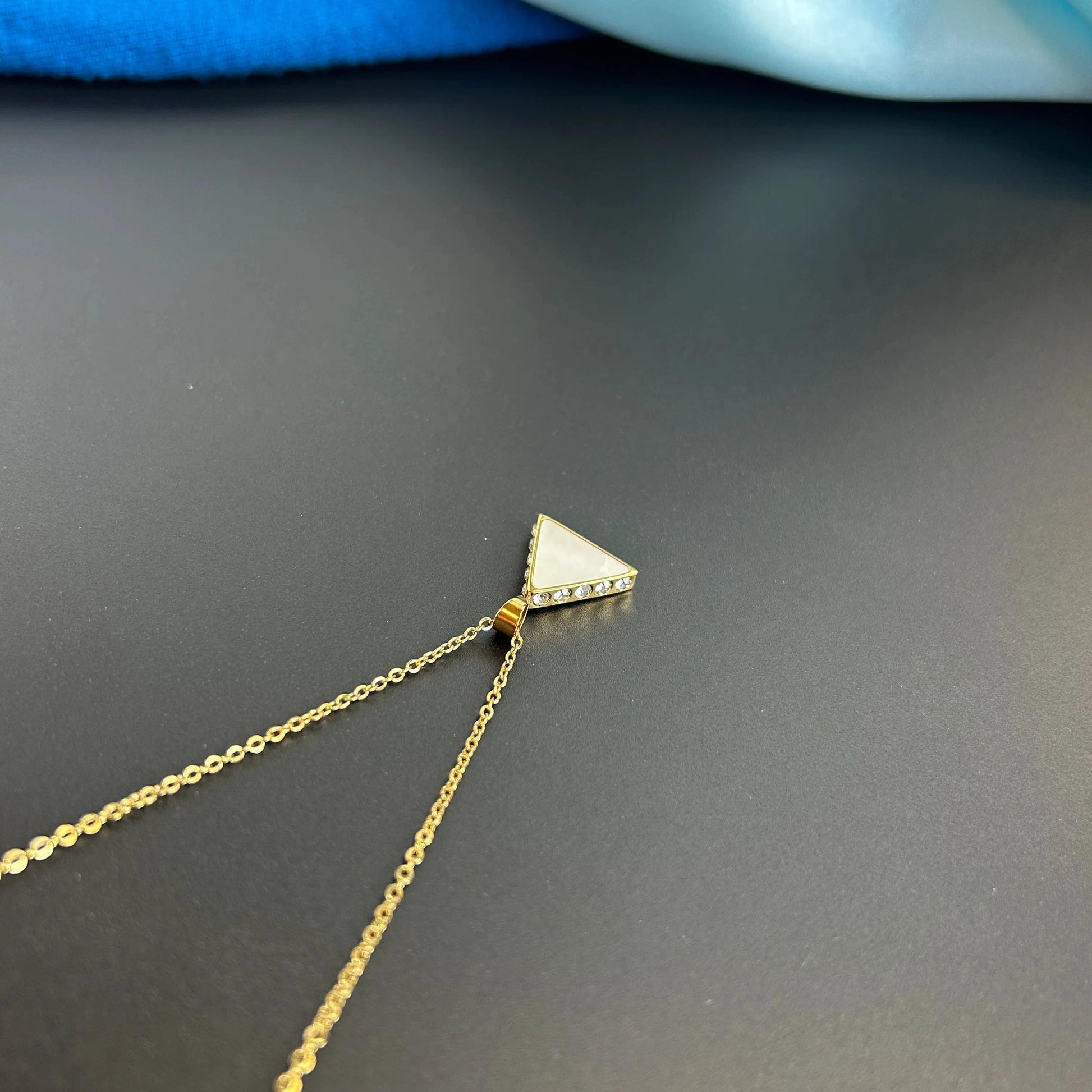 A top down look at the Amelia Gold Pendant Triangle necklace, to see the sparkling clear stones set on the sides. Perfect for every day casual wear.