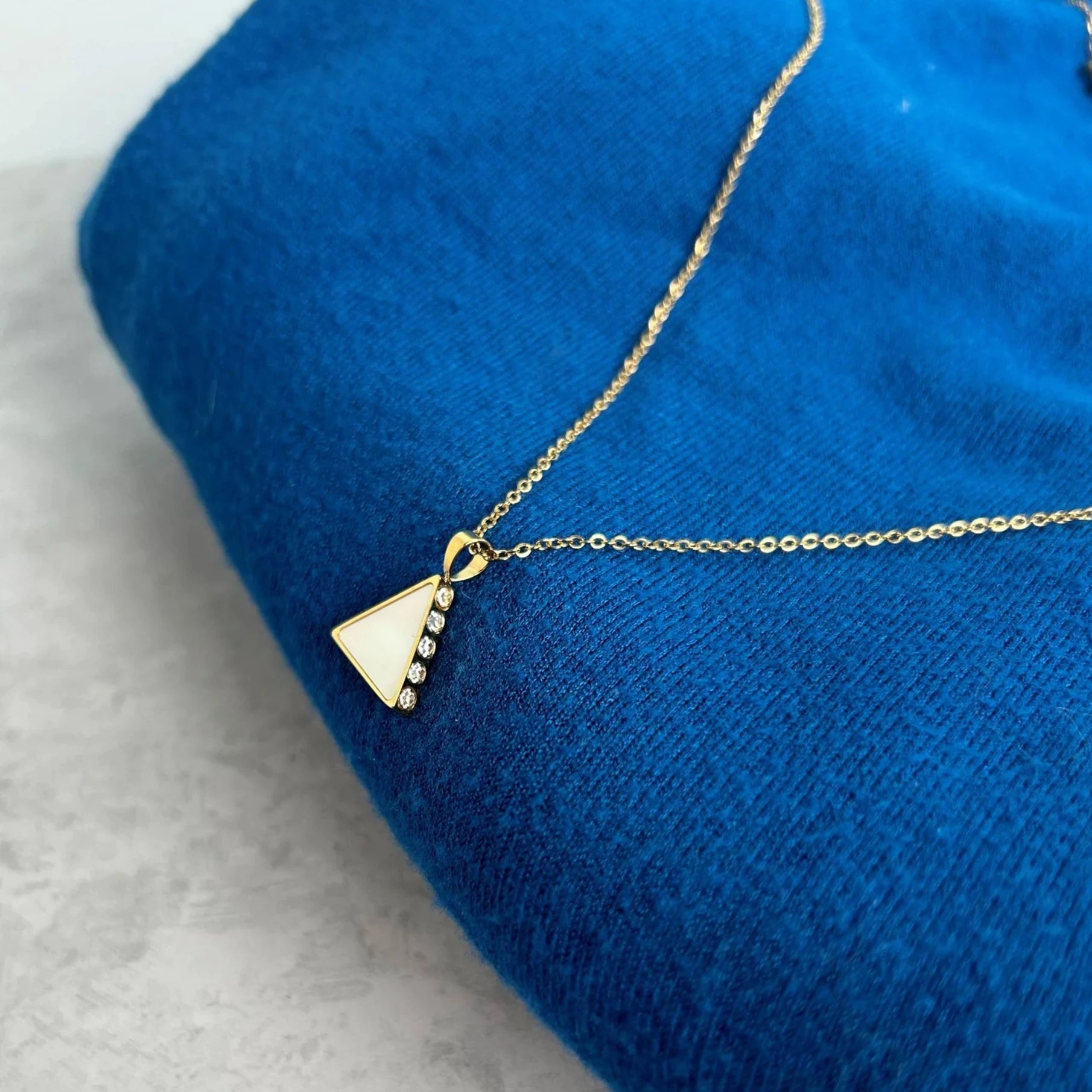 A side view of the chic shimmering stones embedded on the Amelia 18k Gold Triangle pendant necklace. Makes a great gift.