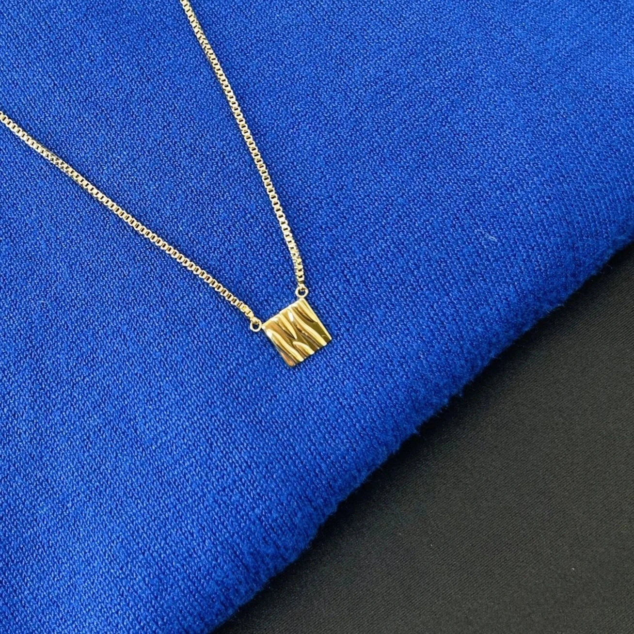 Shining gold pendant necklace standing out beautifully on royal blue