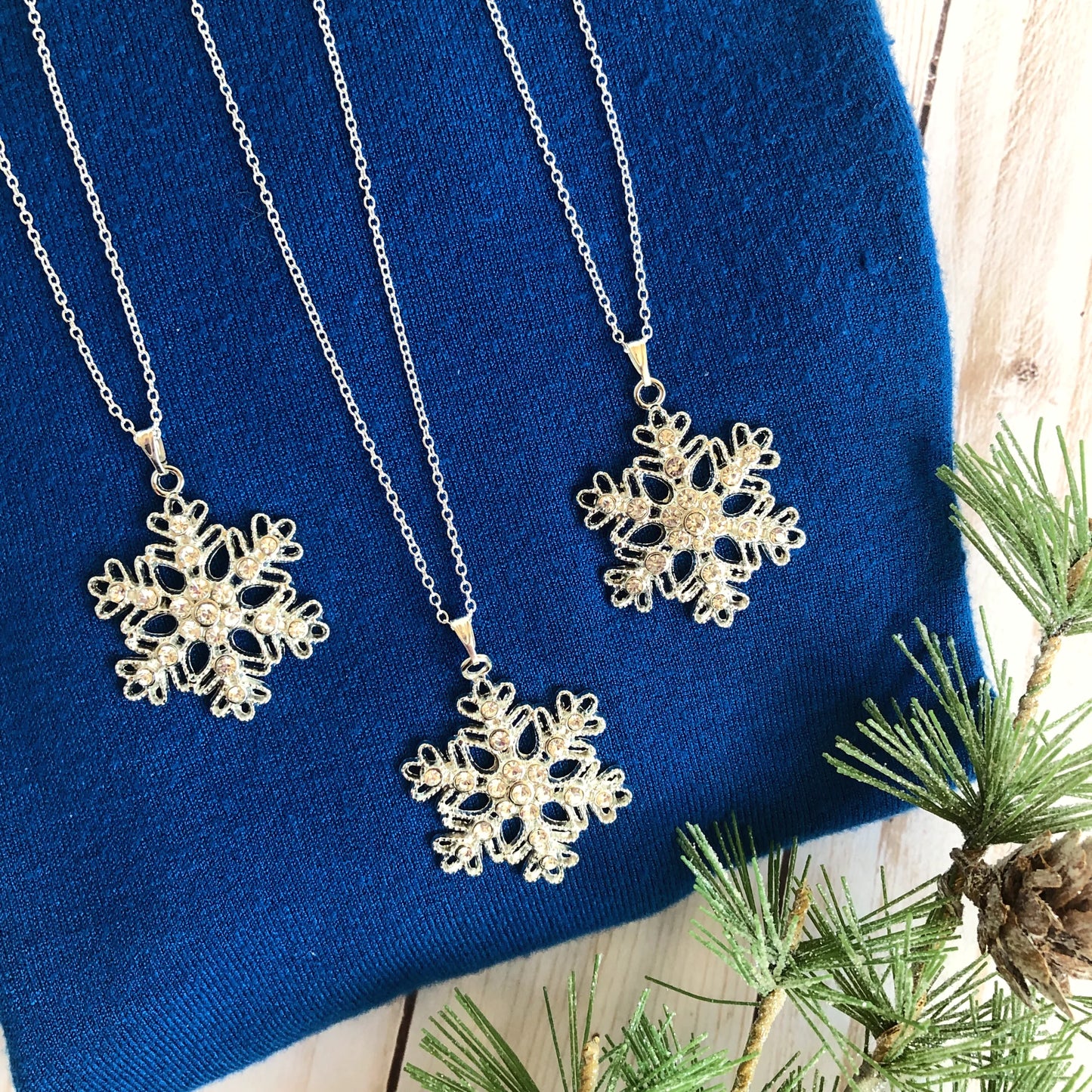 Sparkling silver snowflake pendant necklaces, on a royal blue sweater